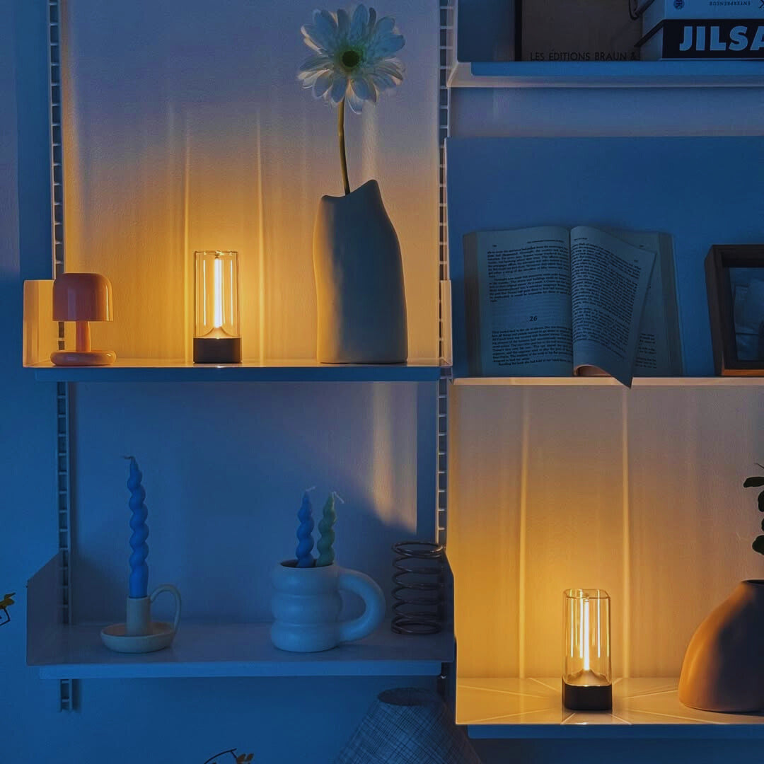Nestled shelves with decorative items including a vase, candles, filament led lights and books in a cozy setting.