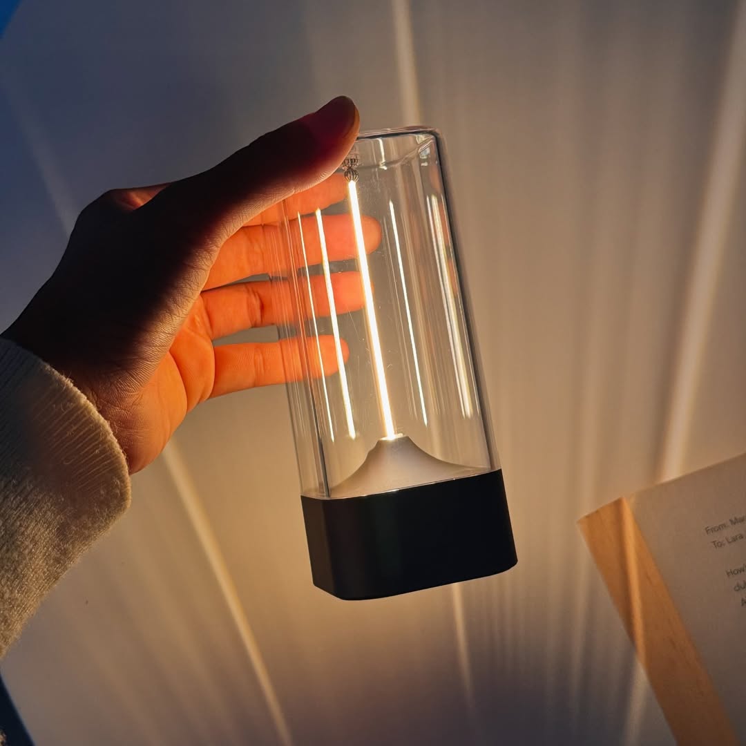 Hand holding a transparent cylindrical light bulb against a white background