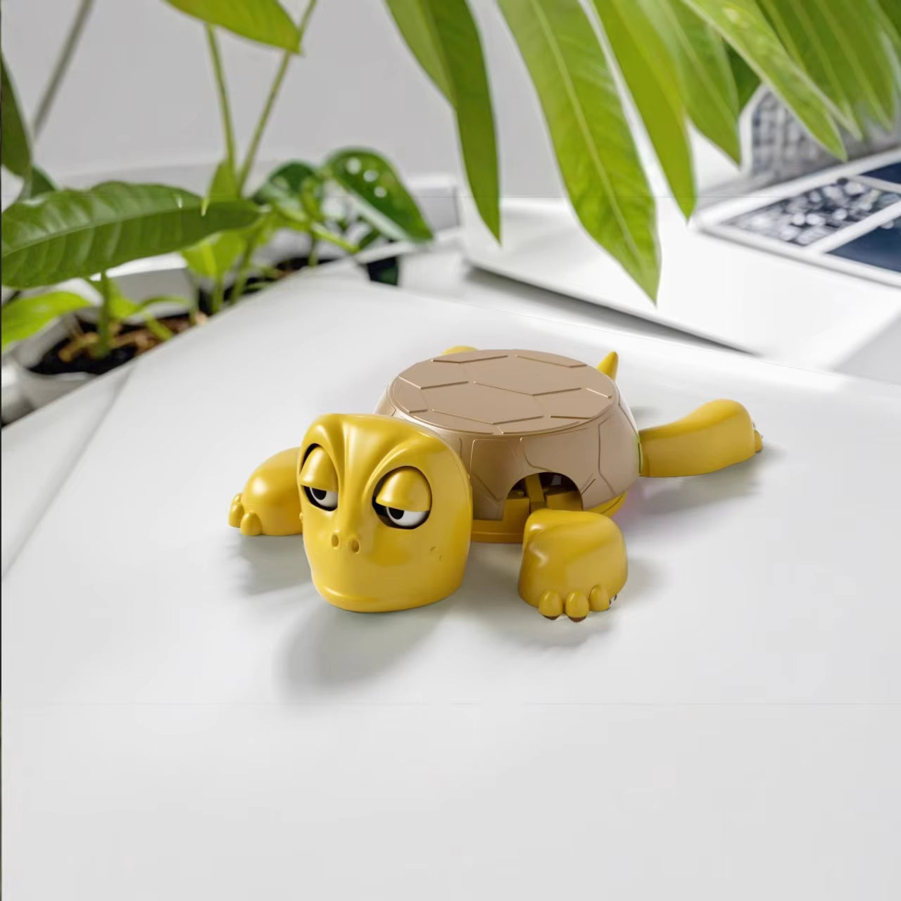 yellow brown turtle coaster on a white surface with plants in the background